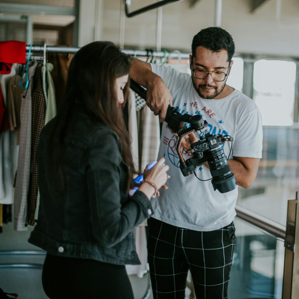 Male photographer with DSLR camera preparing for fashion shoot in an indoor setting.